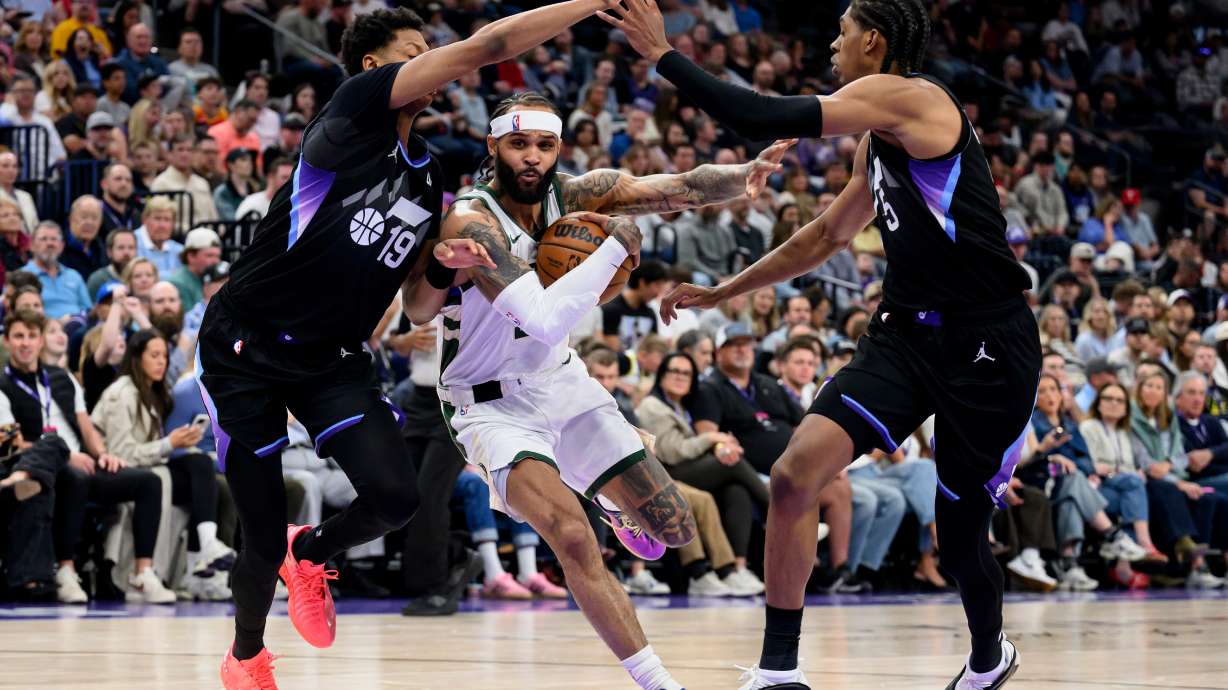 Milwaukee Bucks guard Gary Trent Jr., center, drives to the basket while guarded by Utah Jazz guard Ace Bailey, left, and forward Cody Williams, right, during the first half of an NBA basketball game Thursday, March 19, 2026, in Salt Lake City.