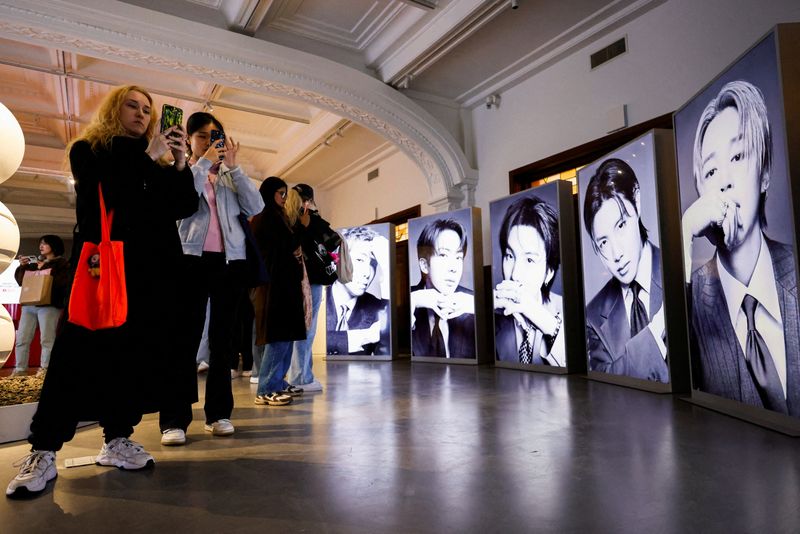 Fans of K-pop boy band BTS, known as ARMY, photograph portraits of the members at a pop-up exhibition ahead of the group's upcoming free comeback concert, "BTS The Comeback Live Arirang," their first performance in more than three years following the completion of mandatory military service, in Seoul, South Korea, on Friday
