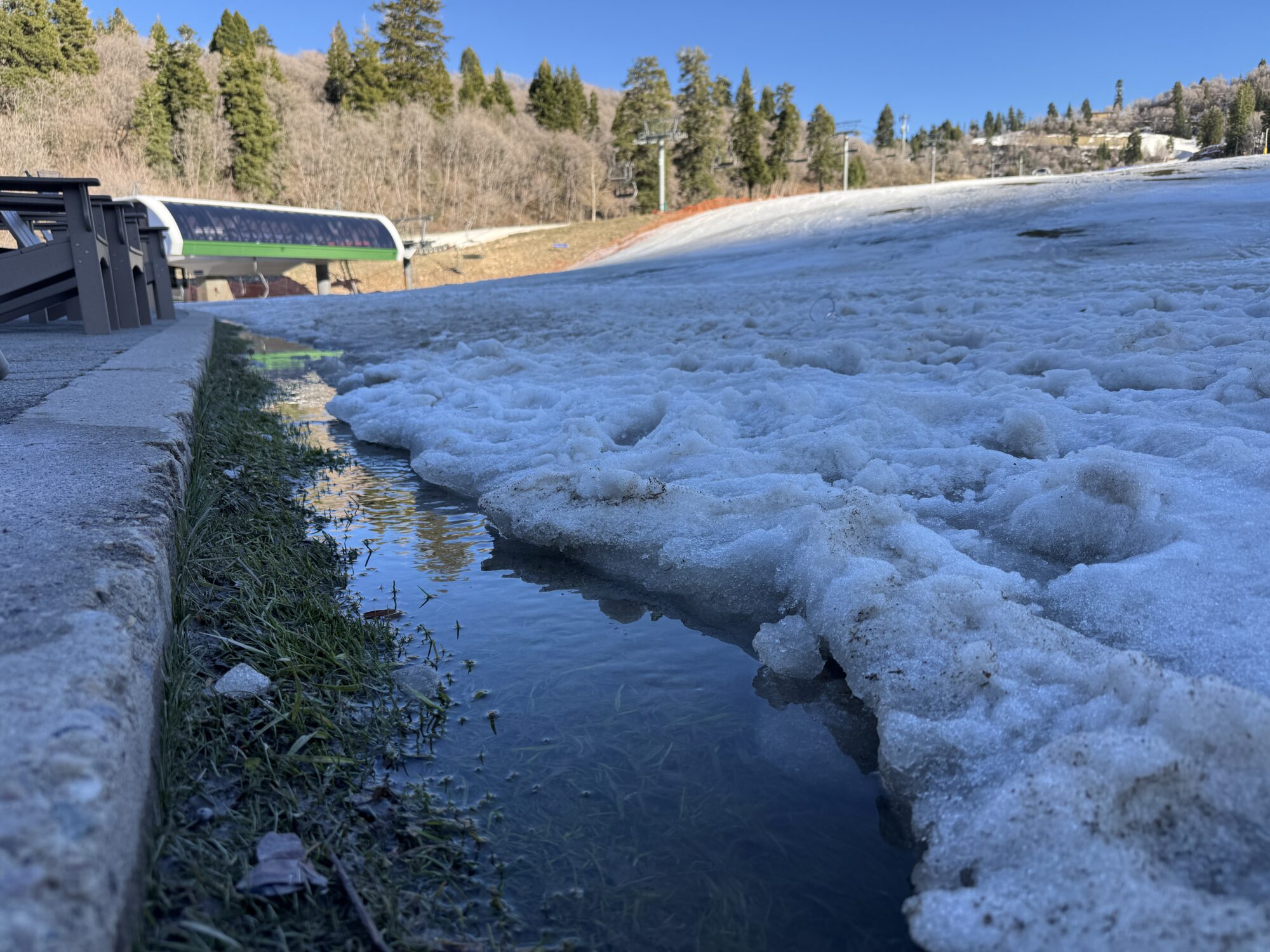 Water runs along the curb at Snowbasin Ski Resort, Thursday. The resort announced it would end its ski season on Sunday.