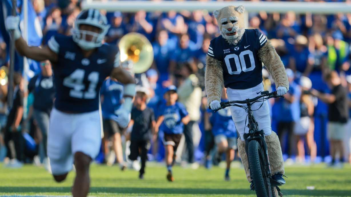 Cosmo the Cougar rides onto the field on a bike before a football game on Aug. 30, 2025. Thanks to social media, the mascot will be joining a local elementary school's bike bus next week.