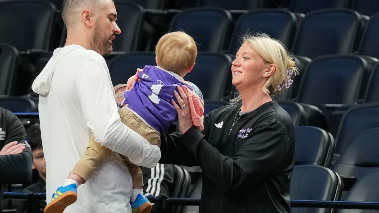 High Point head coach Flynn Clayman, left, hands his son, Quinn, to his wife Katie Clayman, assistant coach for the High Point women's basketball team, right, during practice prior to the first round of the NCAA college basketball tournament on Wednesday, March 18, 2026, in Portland, Ore.