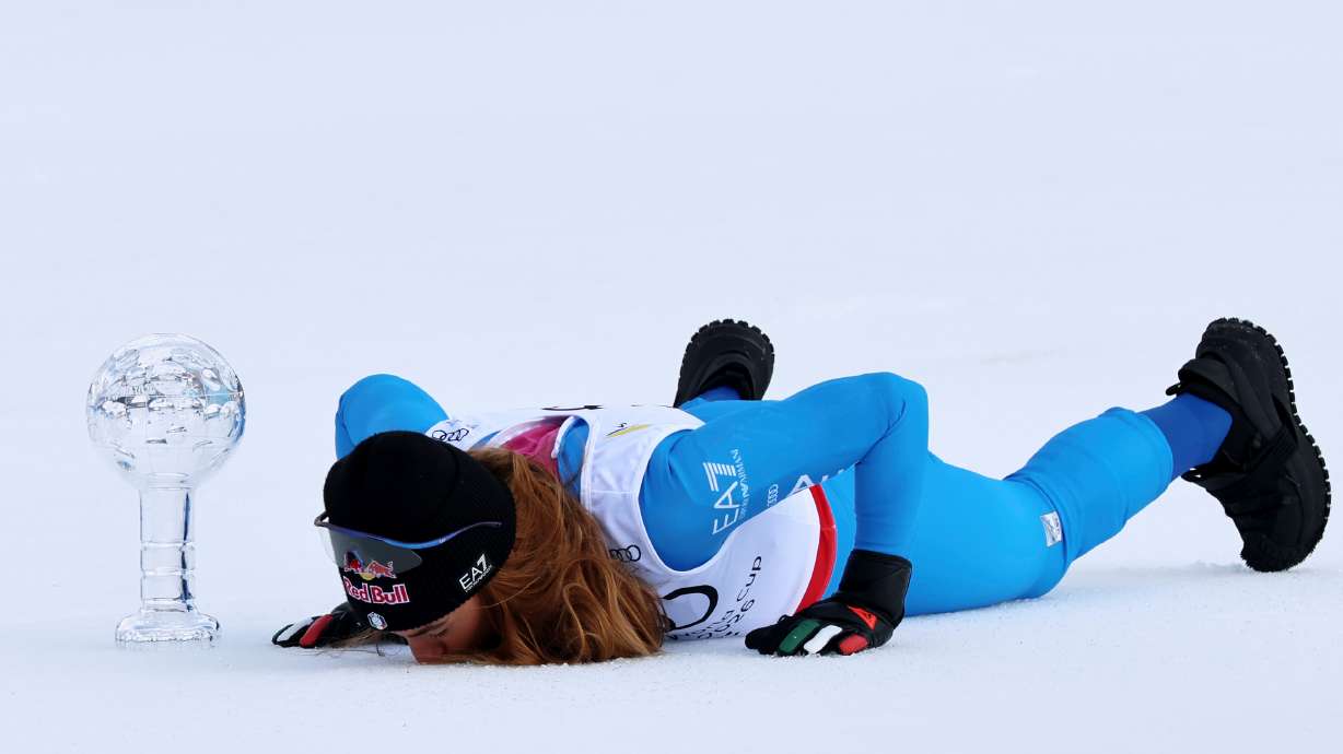 Italy's Sofia Goggia kisses the snow next to the globe trophy for the super-G discipline title after winning an alpine ski, women's super-G race, at the Lillehammer World Cup Finals, in Kvitfjell, Norway, Sunday, March 22, 2026.