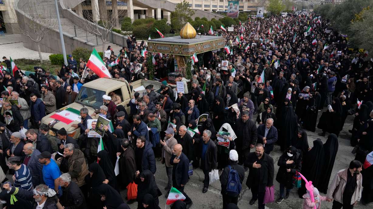 People follow a truck carrying the flag-draped coffins of Gen. Ali Mohammad Naeini, a spokesperson for Iran’s paramilitary Revolutionary Guard and one of his comrades Amir Hossein Bidi , during their funeral procession in Tehran, Iran, Saturday.