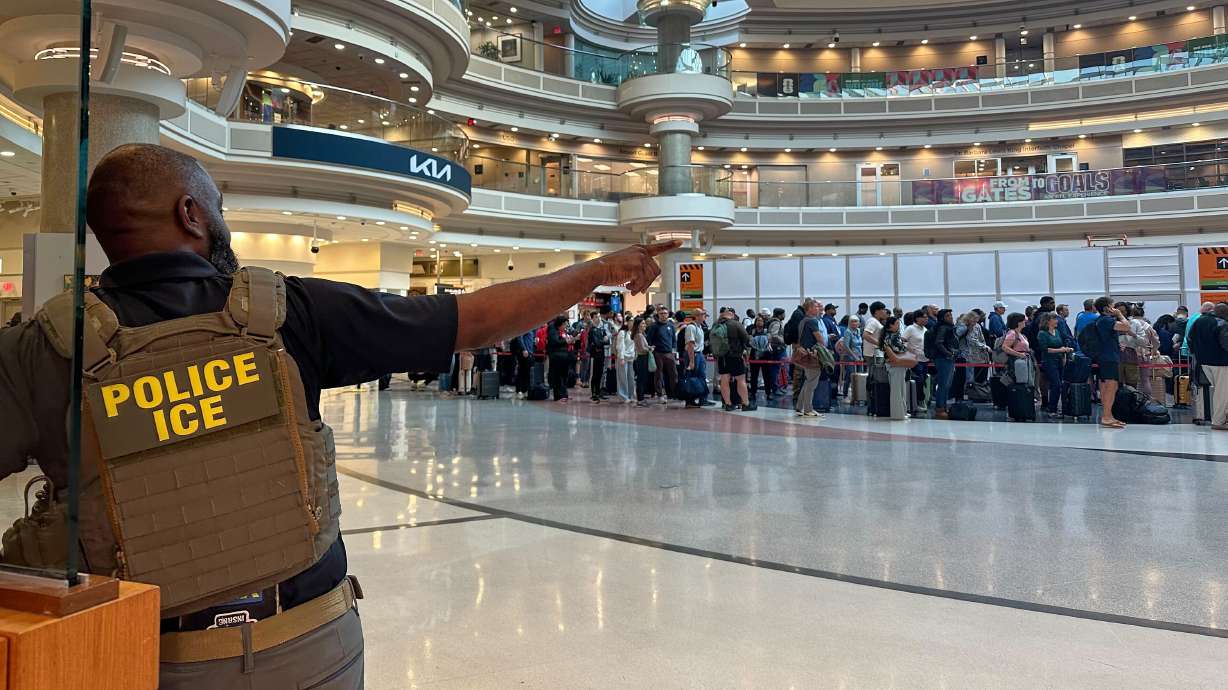 A federal immigration agent is seen as people wait in a TSA line at the Hartsfield-Jackson Atlanta International Airport on Monday.
