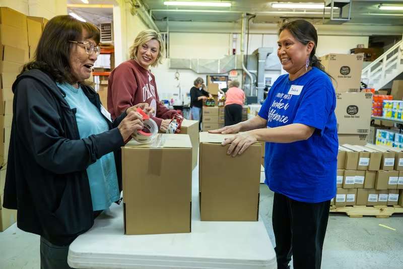 Volunteers Gloria McCabe, KT Steenblik and Debbie work to assemble shipping boxes at Adopt-A-Native-Elder, a nonprofit organization working to help reduce extreme poverty and hardship facing traditional Elders living on the Navajo Reservation in southern Utah and northern Arizona, that will be used in shipping cleaning and other supplies to them, in Salt Lake City on Feb. 27.