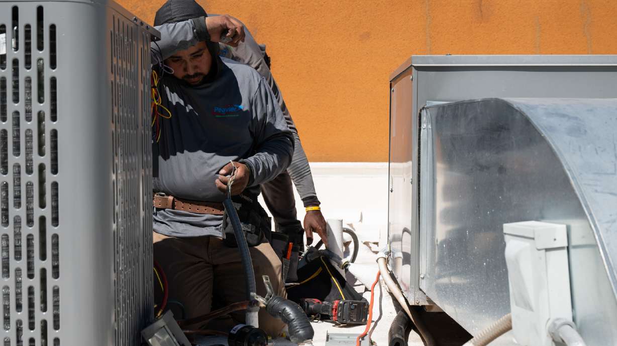 Brian Hermosillo wipes sweat from his brow while installing a new air conditioning unit during record-breaking heat Thursday, in Tempe, Ariz. A huge heat dome is spreading across the United States and it is shattering March temperature records.