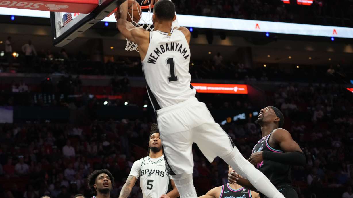 San Antonio Spurs forward Victor Wembanyama (1) dunks over Miami Heat center Bam Adebayo, right, during the first half of an NBA basketball game, Monday, March 23, 2026, in Miami.