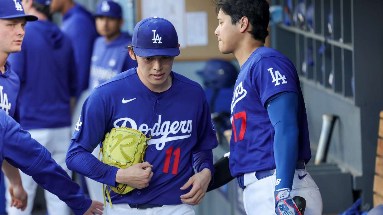Los Angeles Dodgers starting pitcher Roki Sasaki (11) is greeted by designated hitter Shohei Ohtani, right, after being taken off the mound during the first inning of a spring training baseball game against the Los Angeles Angels, Monday, March 23, 2026, in Los Angeles.