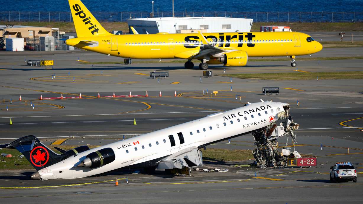 A Spirit Airlines jet taxis past an Air Canada Express jet sitting on the side of a runway, Tuesday, where it had collided with a Port Authority fire truck Sunday night at LaGuardia Airport in New York. Federal investigators said the runway warning system did not trigger prior to the collision.