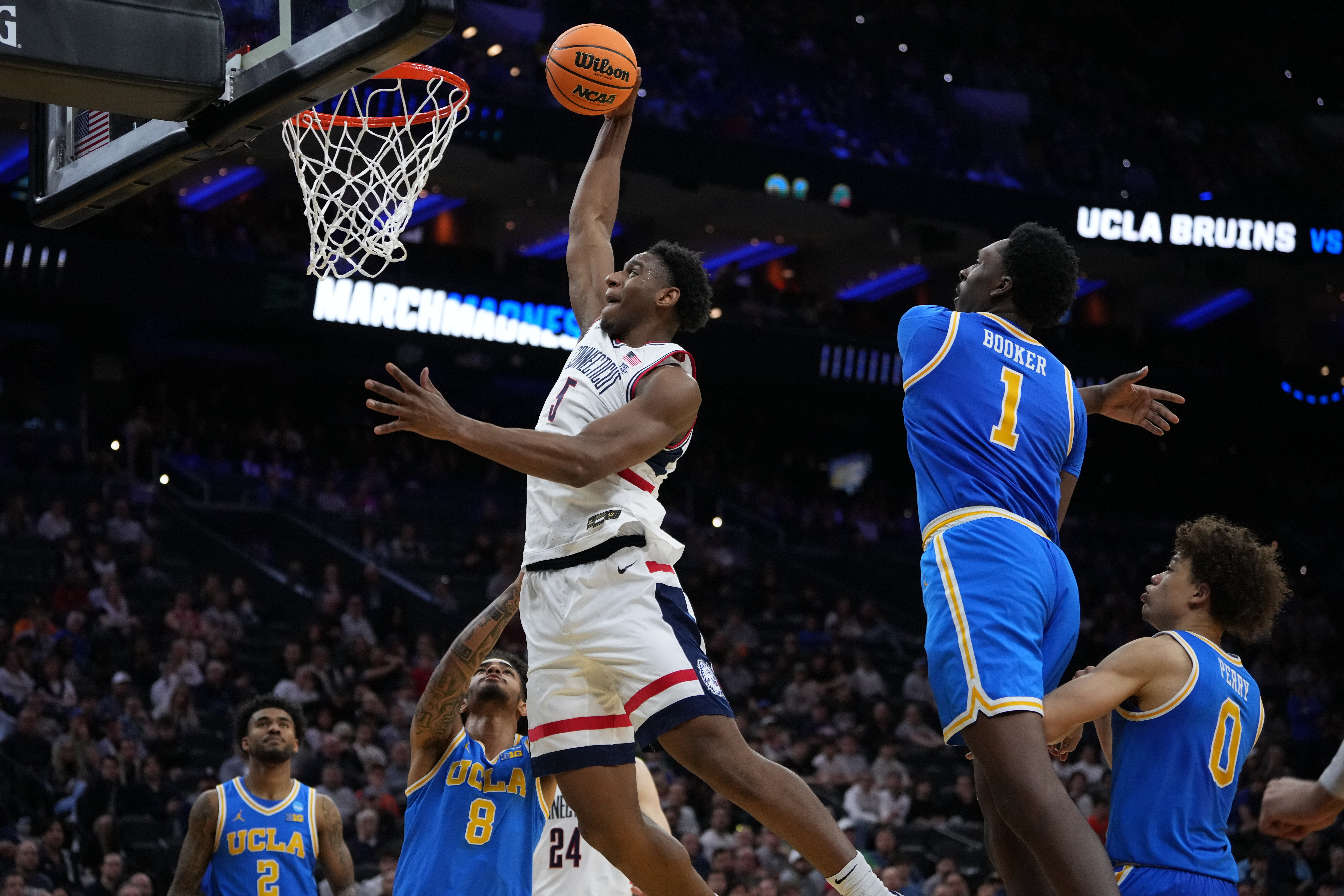 UConn's Tarris Reed Jr. (5) goes up for a dunk [ast UCLA's Xavier Booker (1) and Eric Freeny (8) during the second half in the second round of the NCAA college basketball tournament, Sunday, March 22, 2026, in Philadelphia. 