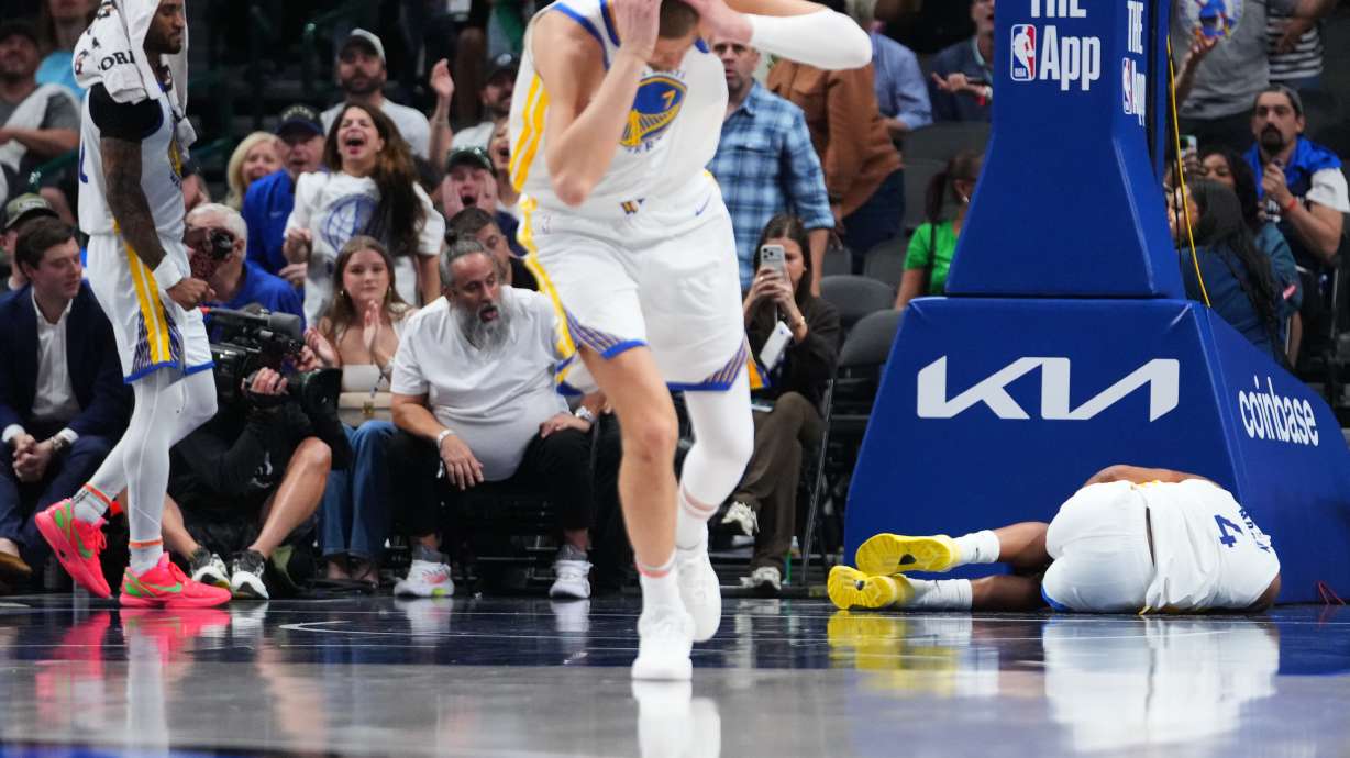 Golden State Warriors center Kristaps Porzingis, center, and guard Gary Payton II, left, react after guard Moses Moody (4) suffered an injury during overtime of an NBA basketball game against the Dallas Mavericks Monday, March 23, 2026, in Dallas.