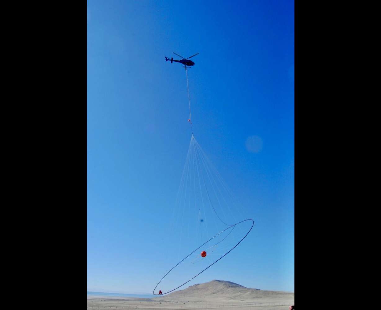 A helicopter lifts off from Antelope Island carrying electromagnetic survey equipment for a geophysical data-gathering mission over Farmington Bay in February 2025.