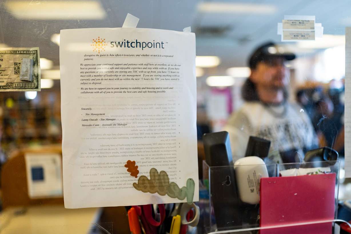 Information for guests is posted near the entrance while Zach Ennis, swing shift lead, works at Switchpoint's Salt Lake Overflow Shelter in West Valley City on Wednesday.