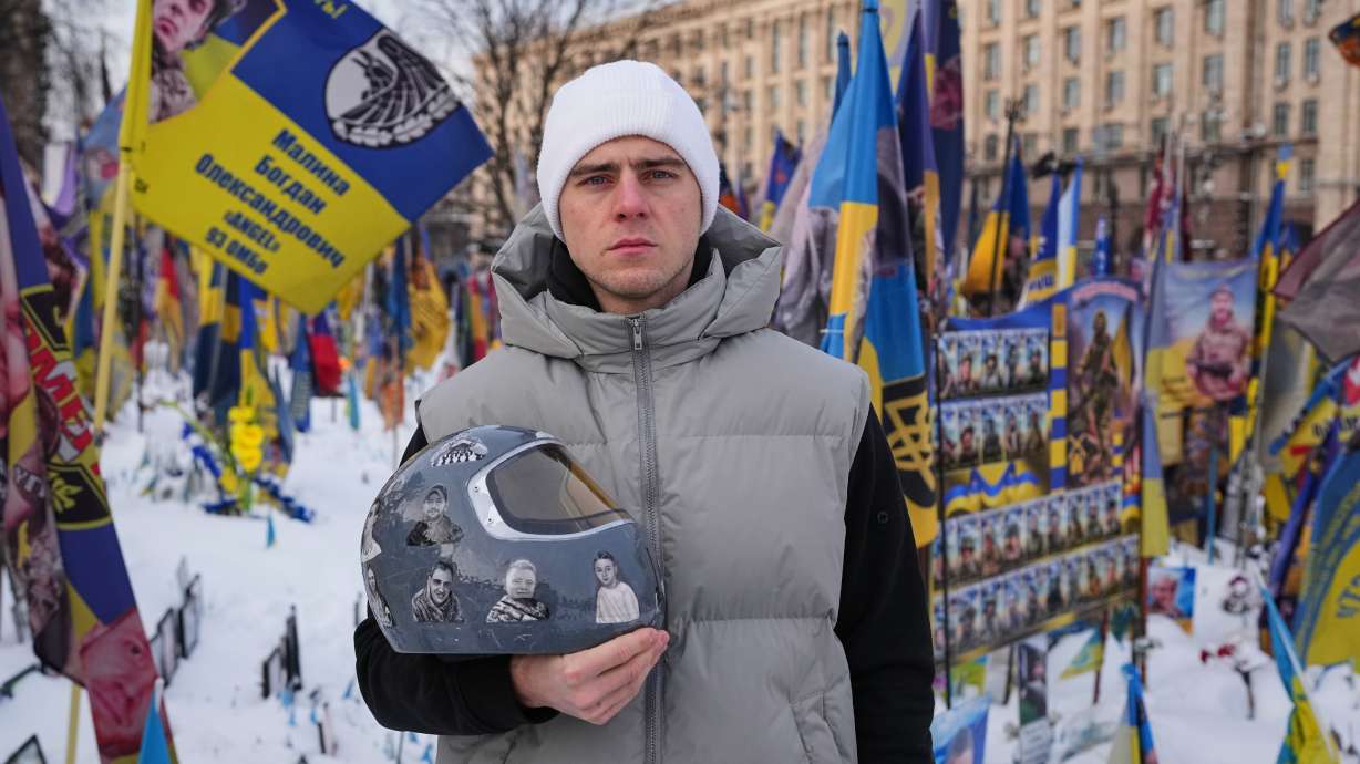 FILE - Ukrainian skeleton athlete Vladyslav Heraskevych holds his crash helmet as he stands outside an improvised memorial to fallen soldiers killed in the war at Independence square in Kyiv, Ukraine, Feb. 18, 2026.