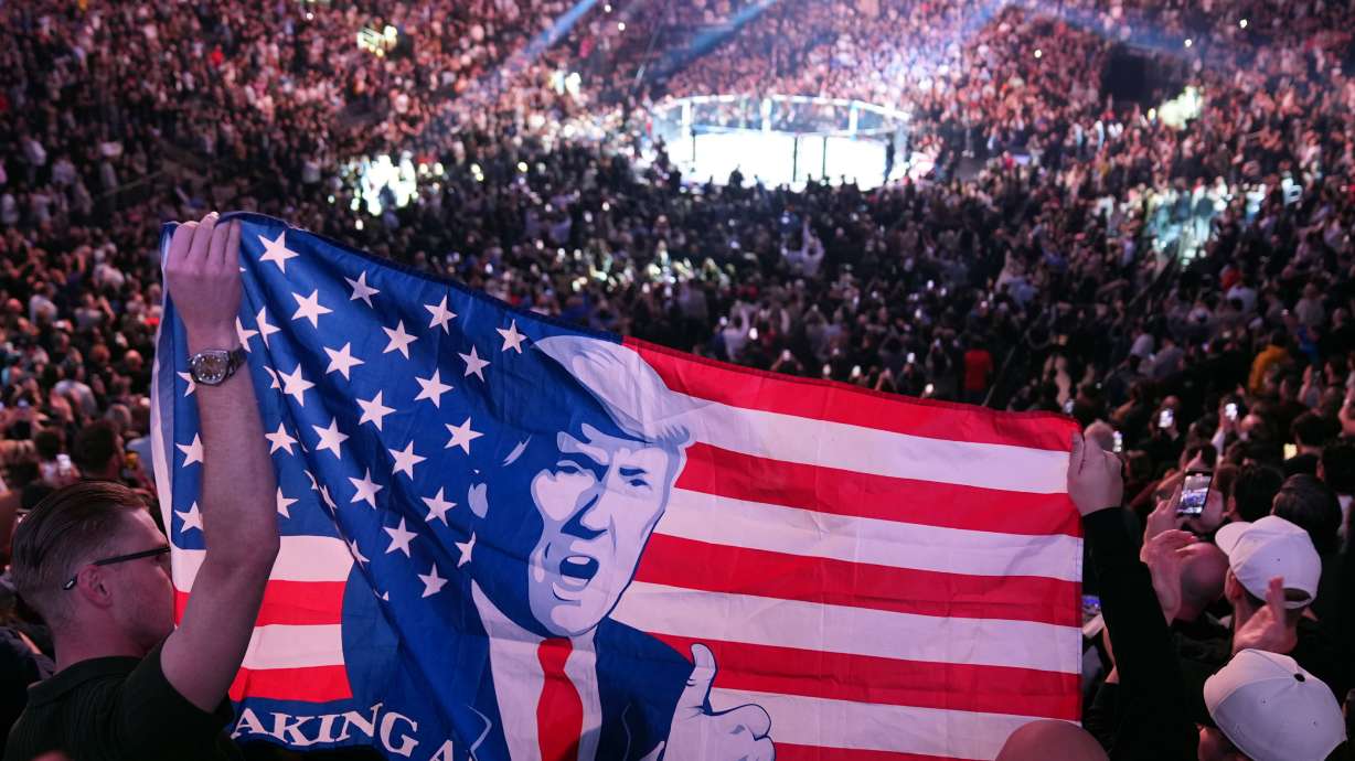 FILE - People hold a flag as President-elect Donald Trump arrives at UFC 309 at Madison Square Garden, Nov. 16, 2024, in New York.