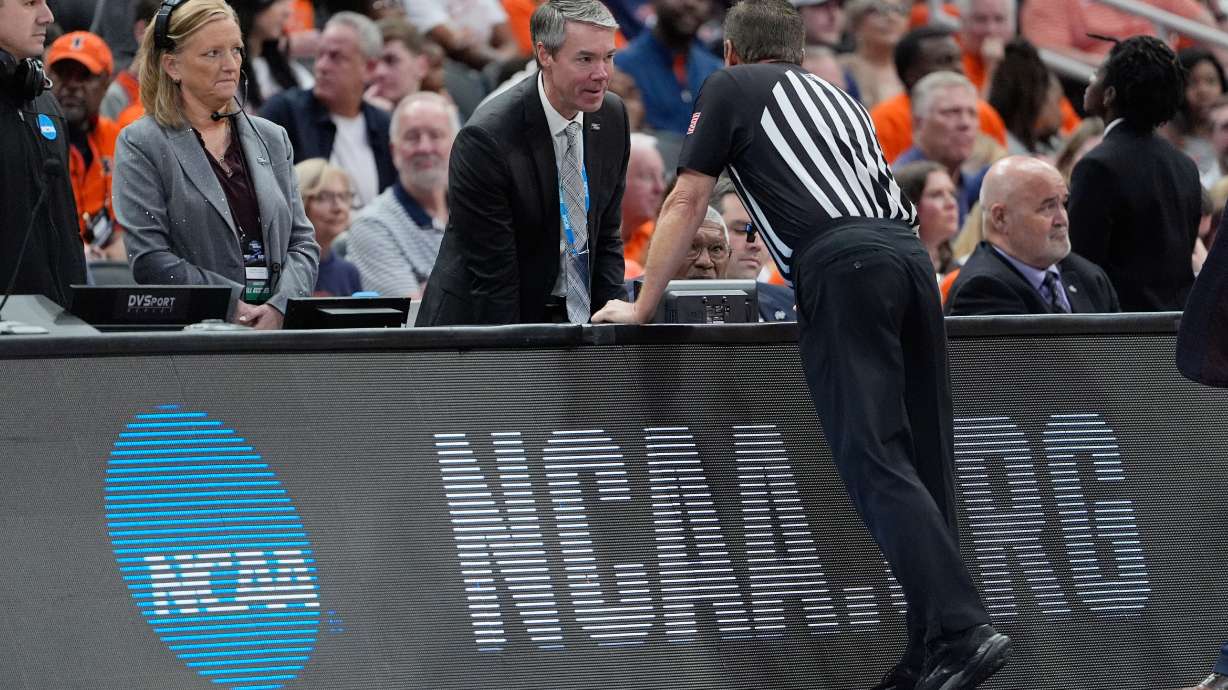 A referee talks with the scorer's table during an official's timeout due to a broken shot clock horn during the first half of an Elite Eight game between Iowa and Illinois in the NCAA college basketball tournament Saturday, March 28, 2026, in Houston.