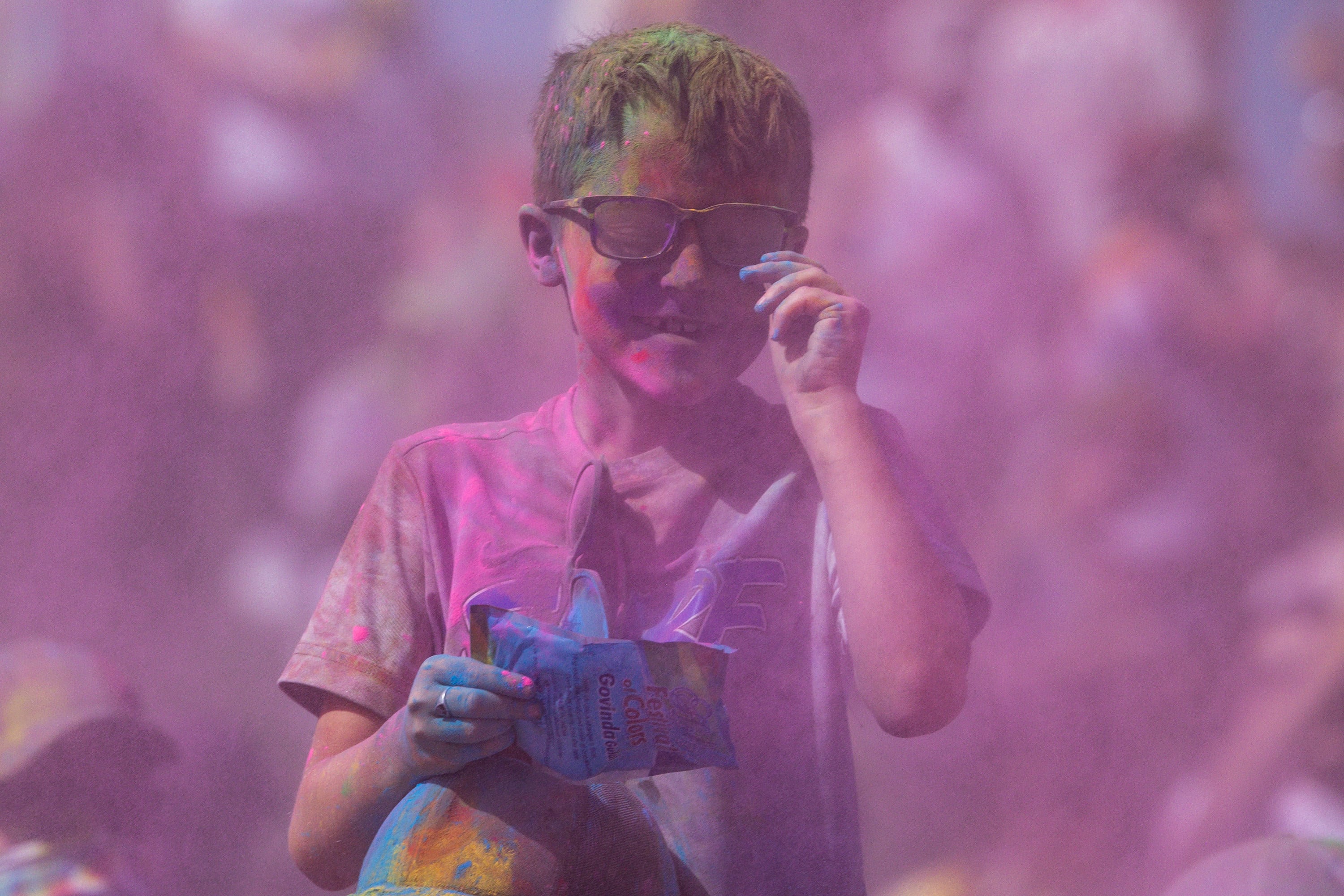 A boy smiles as he wipes his glasses after having color dumped on his head as people celebrate Holi at the Sri Sri Radha Krishna Temple in Spanish Fork on Saturday.