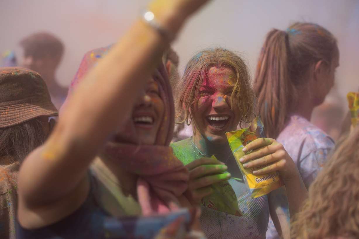 People smile as they emerge from a cloud of colored powder after participating in a color-throwing celebration of Holi at the Sri Sri Radha Krishna Temple in Spanish Fork on Saturday.