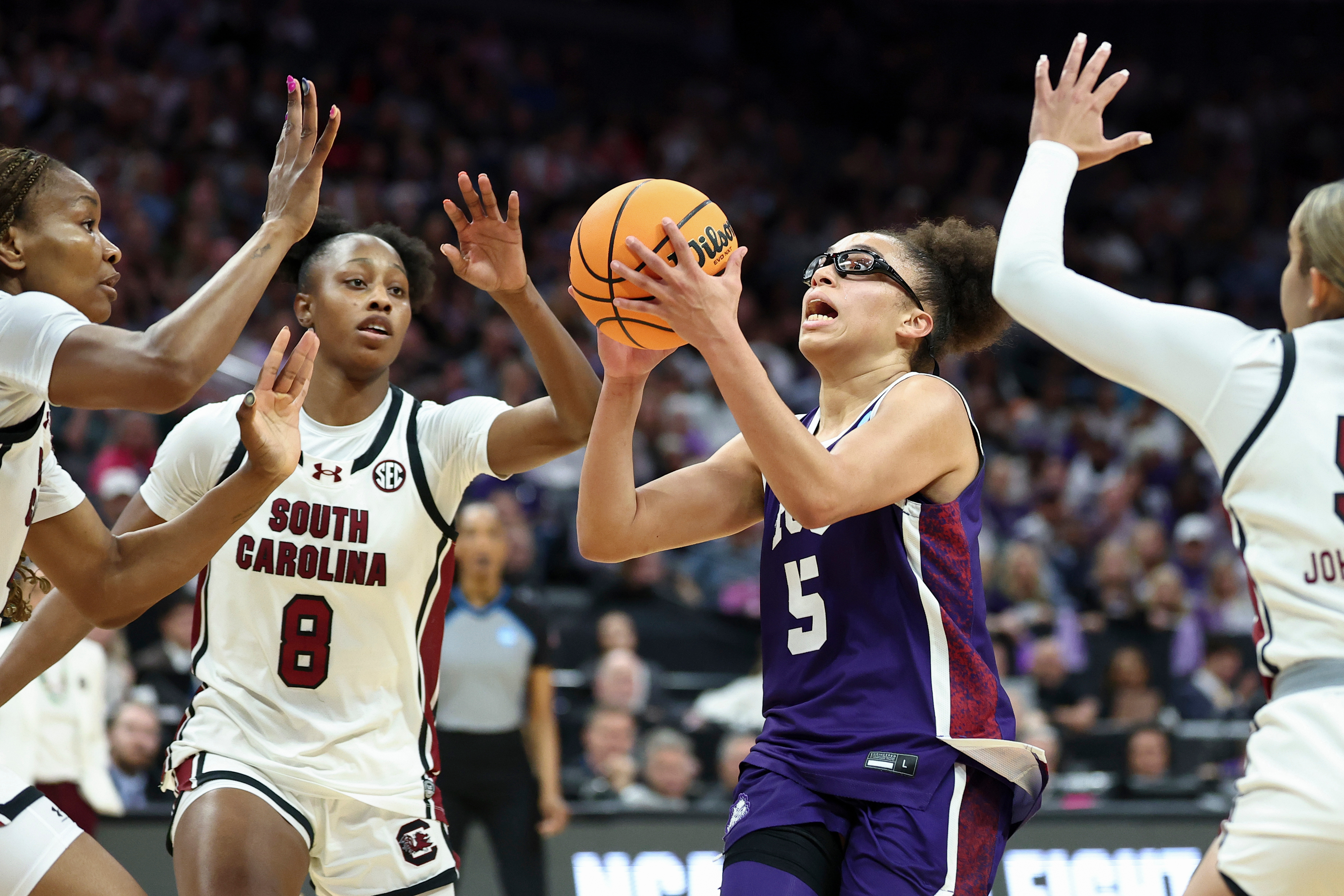 TCU guard Olivia Miles (5) drives to the basket with South Carolina forwards Joyce Edwards (8) and Maryam Dauda, left, defending during the first half in the Elite Eight of the NCAA college basketball tournament Monday, March 30, 2026, in Sacramento, Calif. 