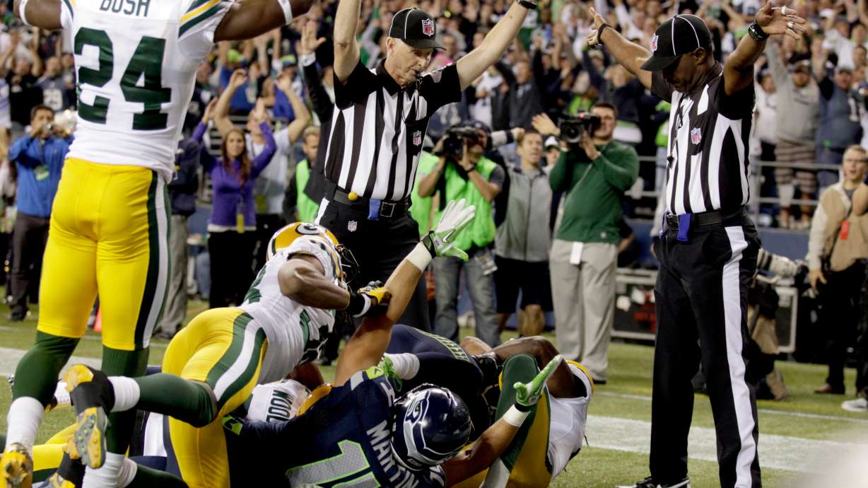 FILE - Officials signal a touchdown by Seattle Seahawks wide receiver Golden Tate, obscured, on the last play of an NFL football game against the Green Bay Packers, Monday, Sept. 24, 2012, in Seattle.