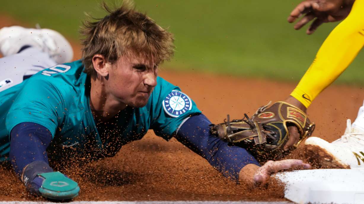 FILE - Seattle Mariners' Colt Emerson slides safely into third on a single from Samad Taylor during the second inning of a spring training baseball game against the San Diego Padres, Feb. 28, 2025, in Peoria, Ariz.