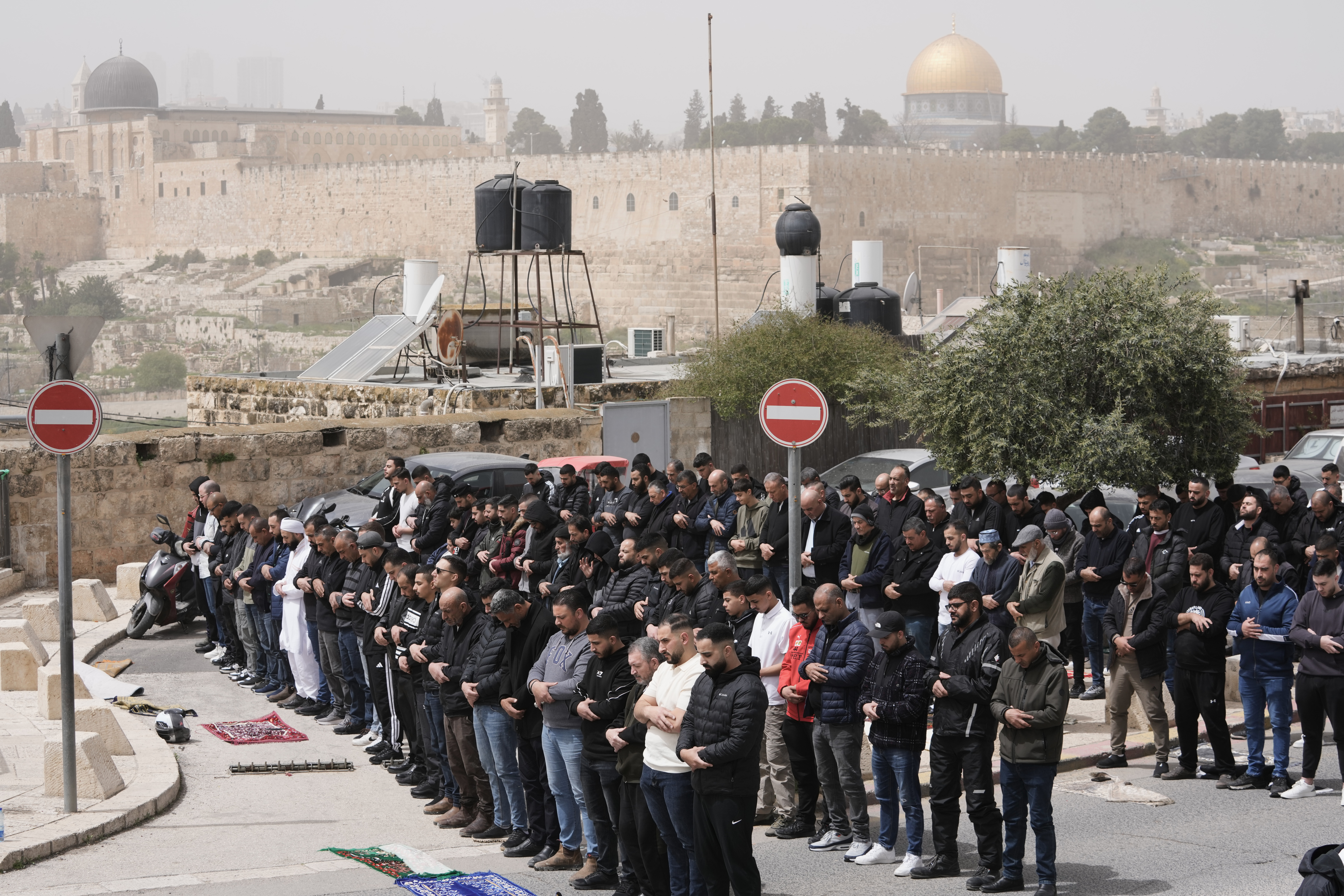 Palestinian Muslims attend Friday prayers outside Jerusalem's Old City due to restrictions linked to the Iran war, Friday. An Israeli drone strike in Lebanon killed two people attending Friday worship.