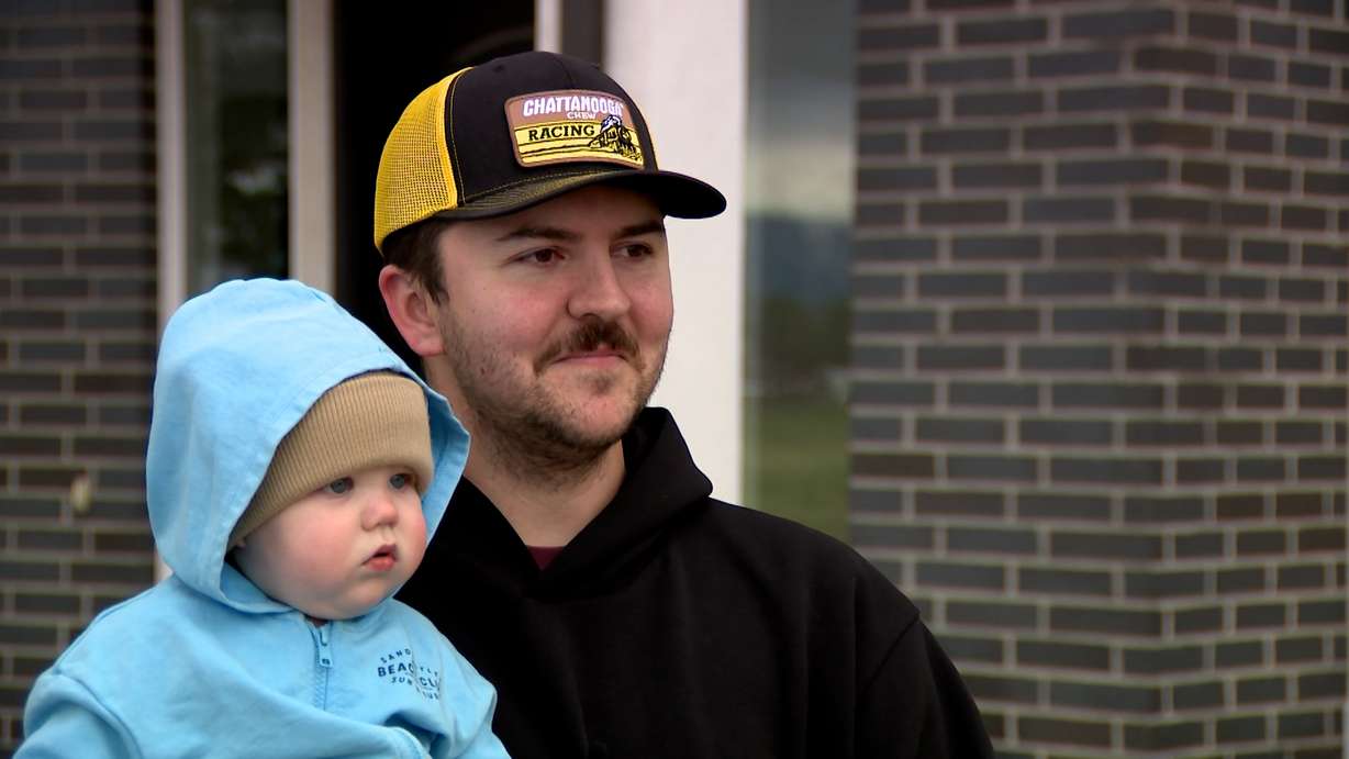 Braden Christensen speaks with KSL Thursday in Lehi while holding his son, Baker.
