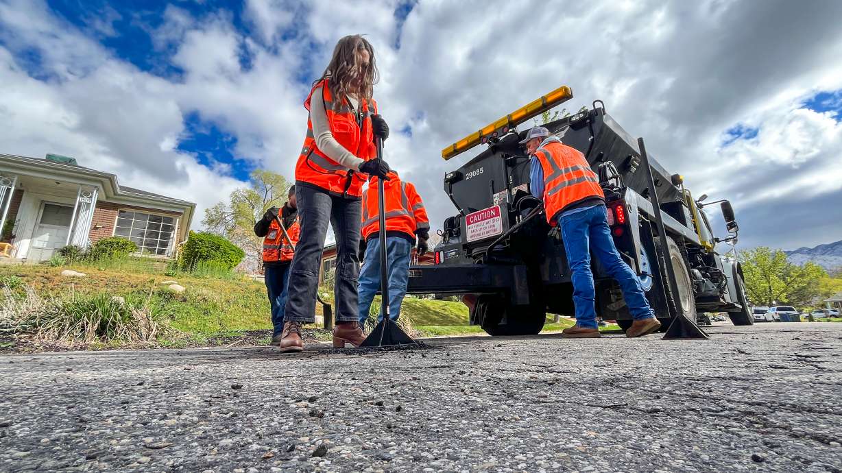 Salt Lake City Mayor Erin Mendenhall helps city streets employees fill a pothole in Salt Lake City's Sugar House neighborhood on Friday. The city will hold its annual "Pothole Palooza" next week, filling as many potholes as possible on city streets.