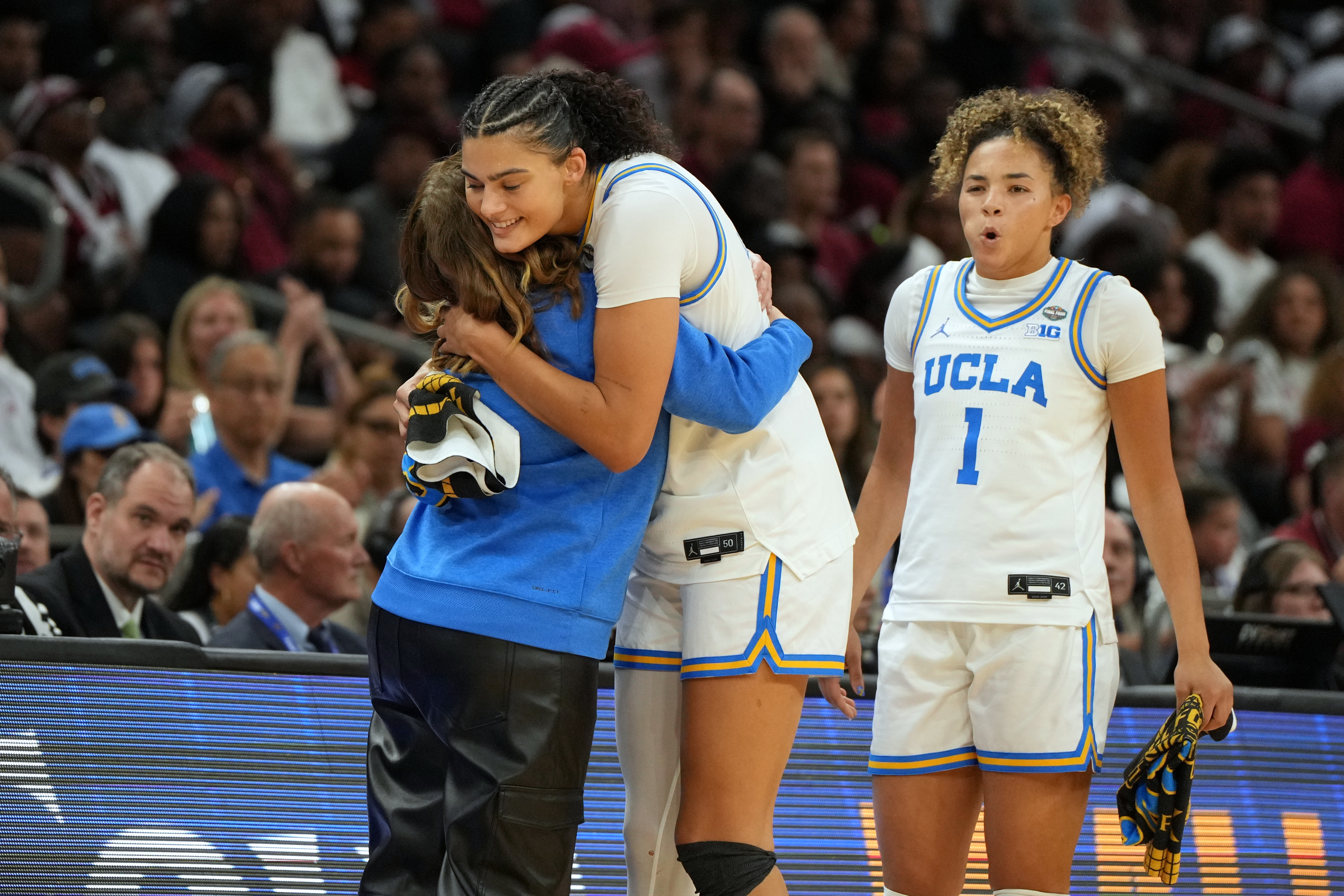 UCLA head coach Cori Close, left, hugs UCLA center Lauren Betts (51) during the second half of the women's National Championship Final Four NCAA college basketball tournament game against South Carolina, Sunday, April 5, 2026, in Phoenix.