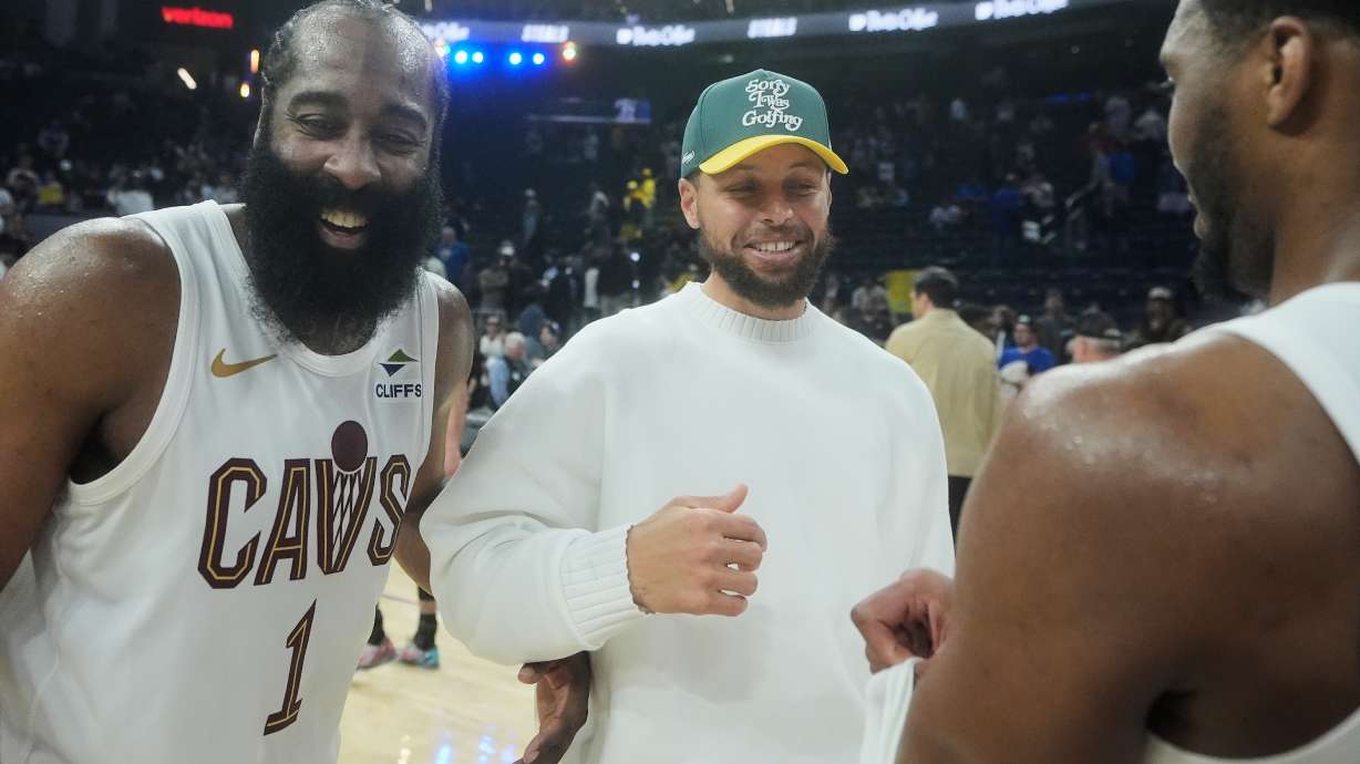 Injured Golden State Warriors guard Stephen Curry, middle, smiles while talking with Cleveland Cavaliers guard James Harden (1) and guard Donovan Mitchell after an NBA basketball game in San Francisco, Thursday, April 2, 2026.