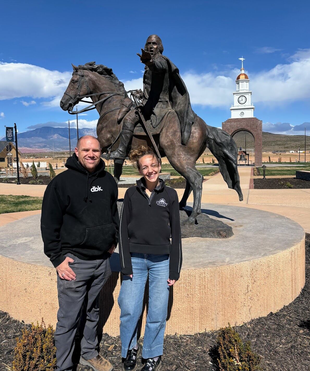 Richard LeBaron, director of operations, and Ellen Jensen, director of marketing, stand in front of a sculpture of George Washington at Liberty Village in Hurricane, Washington County.