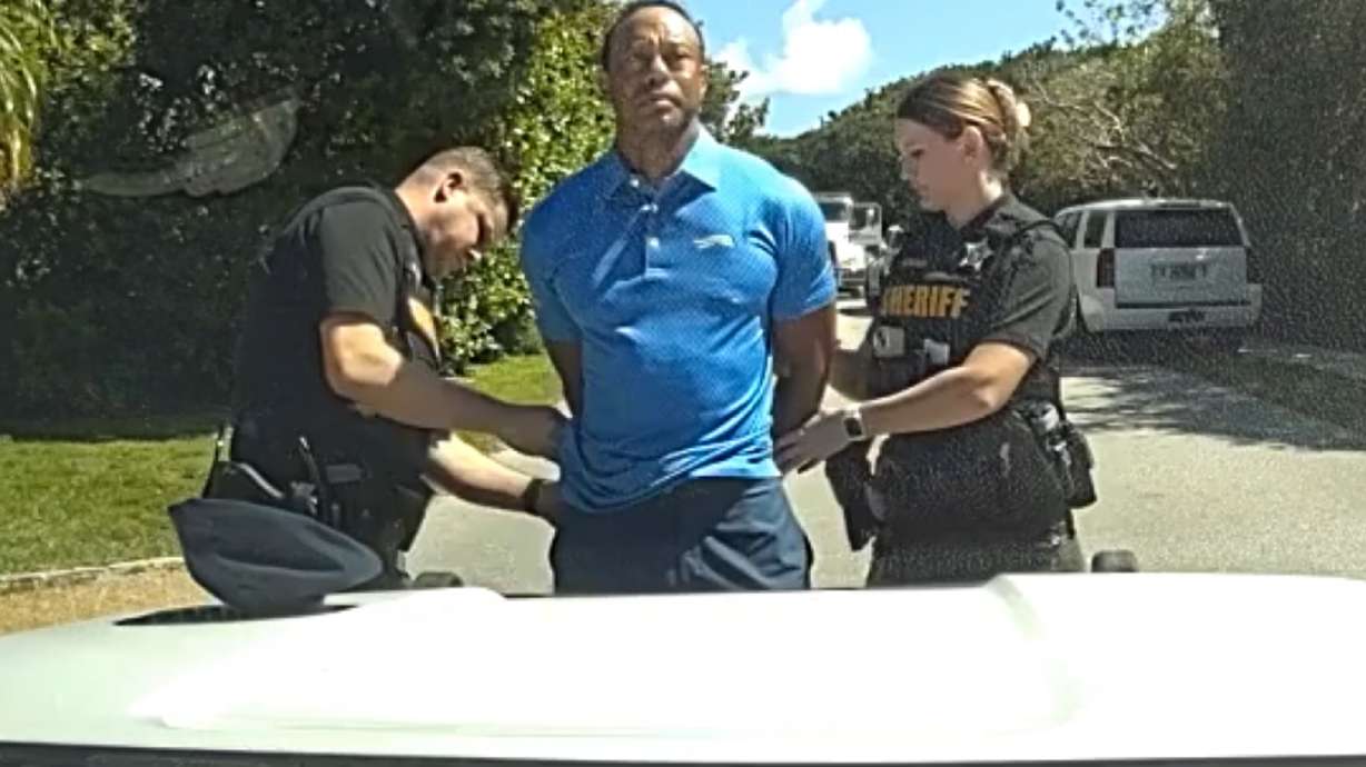 In this image from police body camera video released by the Martin County, Fla., Sheriff's Office, golfer Tiger Woods is taken into custody by sheriff's deputies following a car crash in Jupiter Island, Fla., Friday, March 27, 2026.