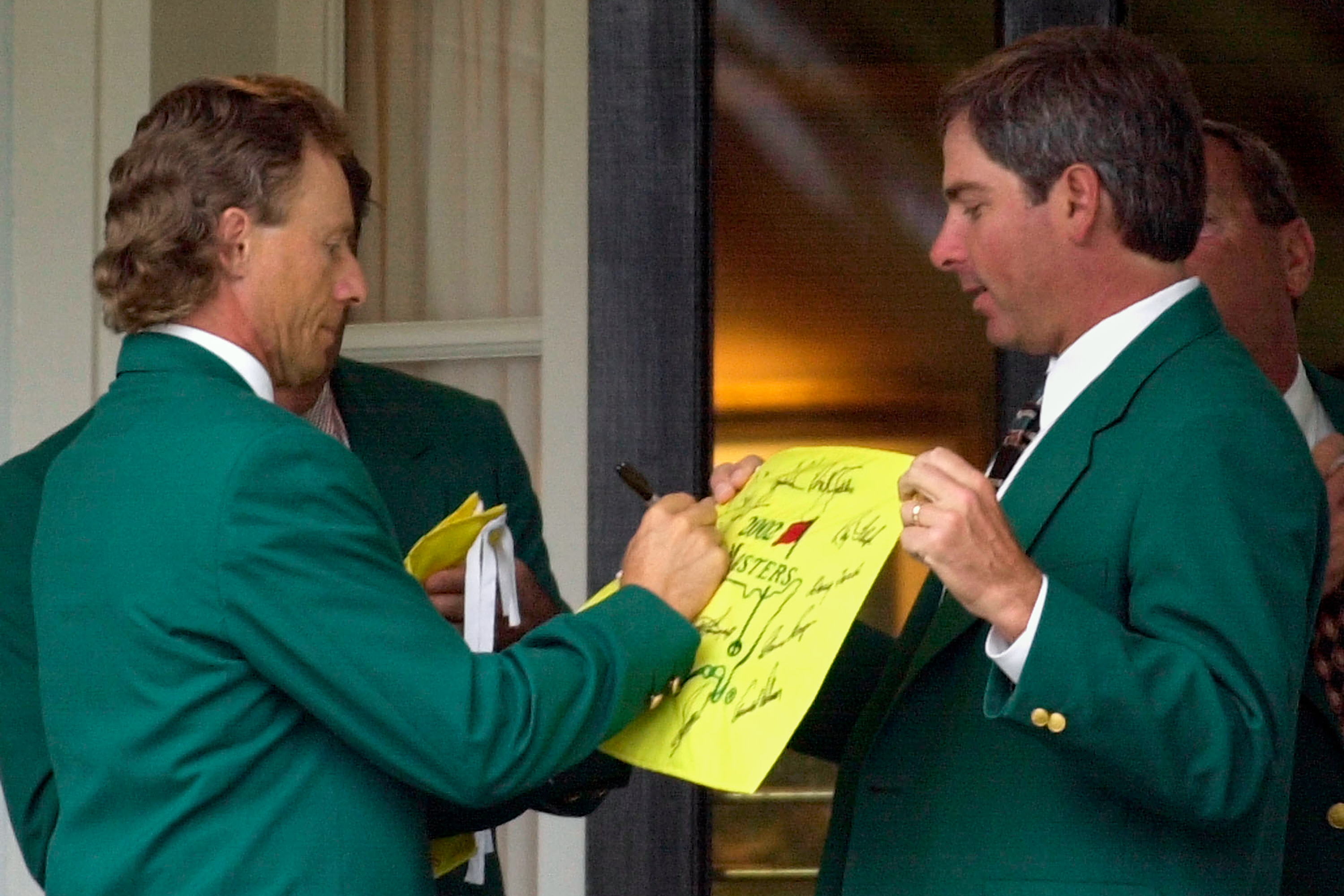 FILE - Former two-time Masters Champion Bernhard Langer, left, signs an autograph for fellow former champion Fred Couples, right, at the Augusta National Golf Club prior to the annual Champions dinner at the 2002 Masters, April 9, 2002, in Augusta, Ga. 