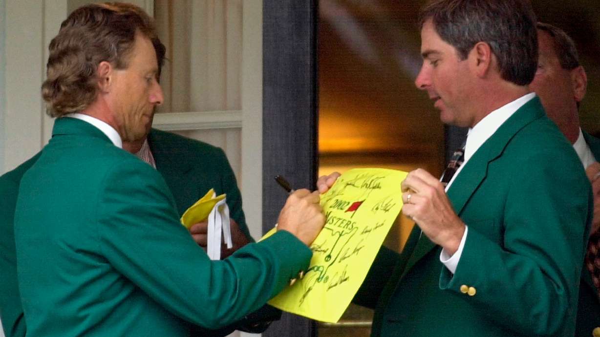 FILE - Former two-time Masters Champion Bernhard Langer, left, signs an autograph for fellow former champion Fred Couples, right, at the Augusta National Golf Club prior to the annual Champions dinner at the 2002 Masters, April 9, 2002, in Augusta, Ga.