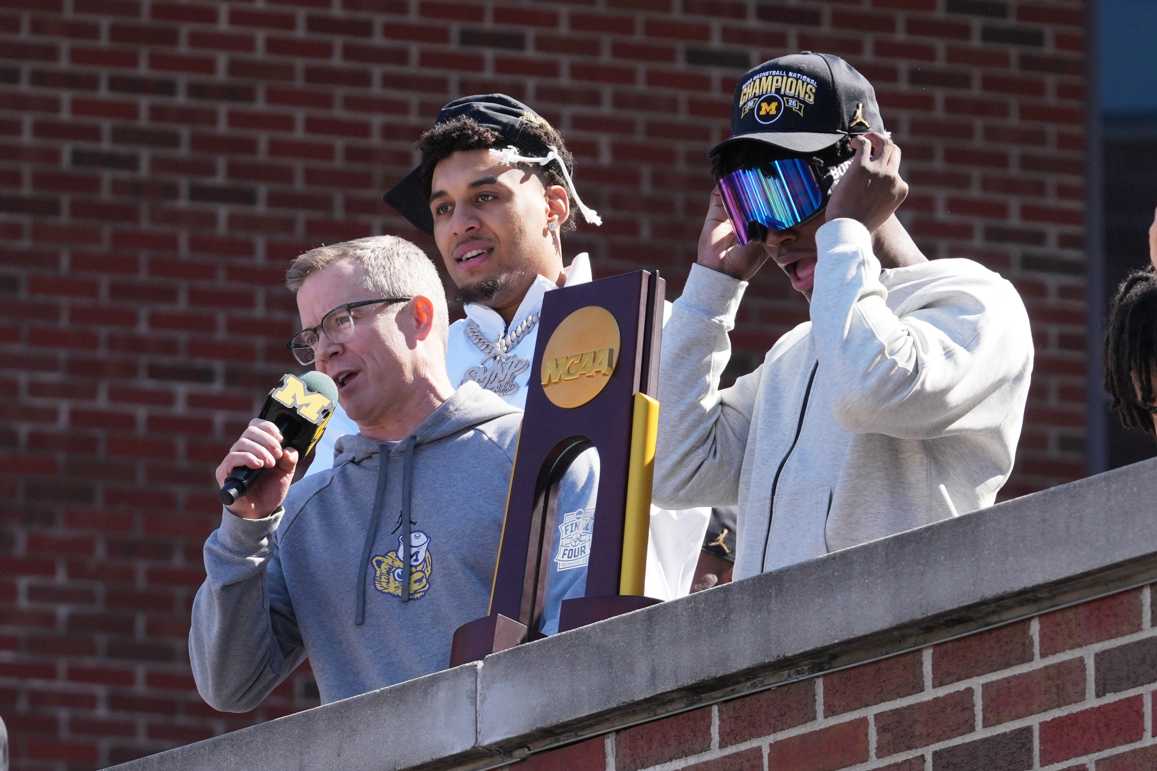 Michigan head coach Dusty May, left, talks to fans as Yaxel Lendeborg, center, and L.J. Cason, right, listen as the team returns to campus Tuesday, April 7, 2026, in Ann Arbor, Mich., the day after defeating UConn at the Final Four of the NCAA college basketball tournament. 