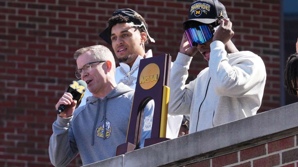 Michigan head coach Dusty May, left, talks to fans as Yaxel Lendeborg, center, and L.J. Cason, right, listen as the team returns to campus Tuesday, April 7, 2026, in Ann Arbor, Mich., the day after defeating UConn at the Final Four of the NCAA college basketball tournament.