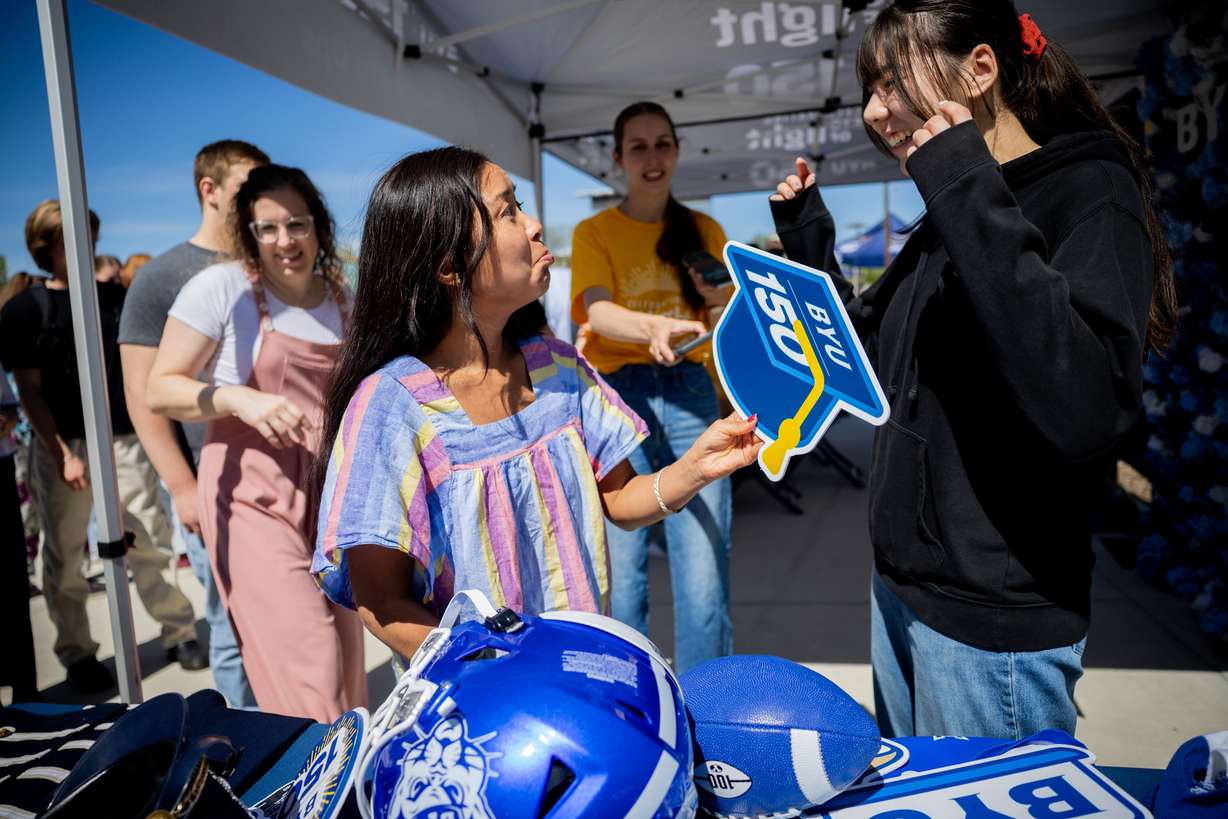 BYU student Sabina Magar reacts as she shows a graduation cap to her friend, BYU student Manami Lehman, during a campus celebration before a time capsule packing party as part of BYU’s 150th anniversary celebration at Brigham Square in Provo on Tuesday. The capsule will be opened in 2075.