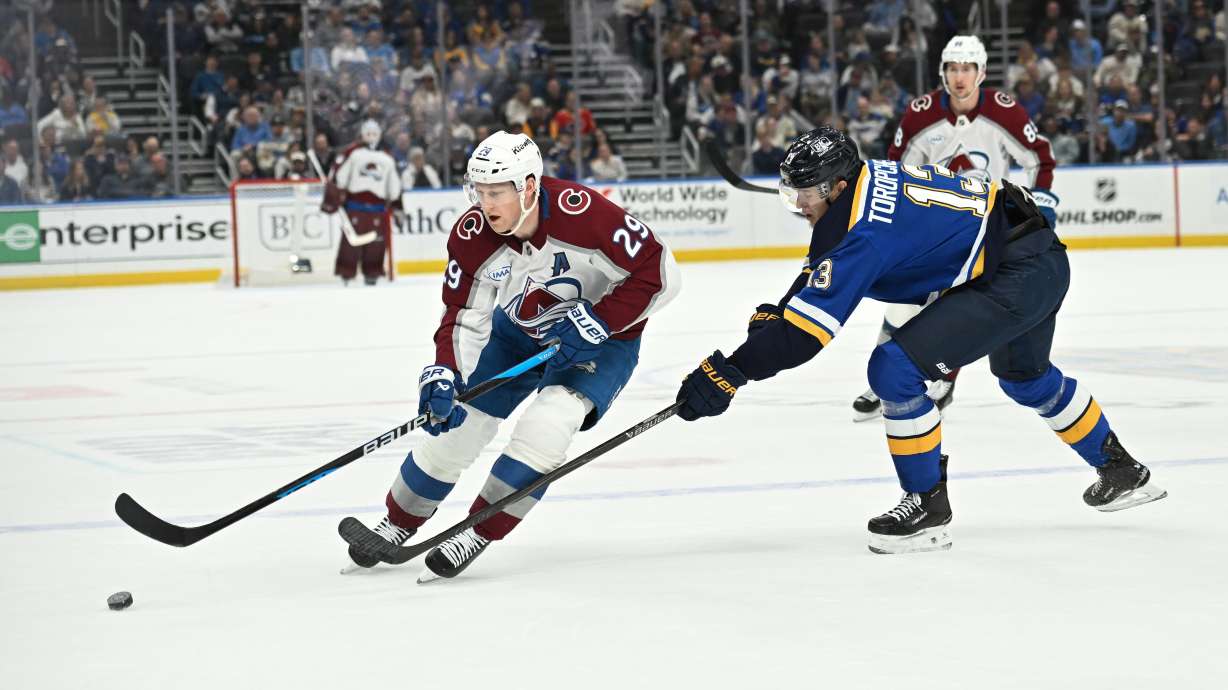 St. Louis Blues' Alexey Toropchenko (13), right, pressures Colorado Avalanche's Nathan MacKinnon (29) during the first period of an NHL hockey game, Tuesday, April 7, 2026, in St. Louis.