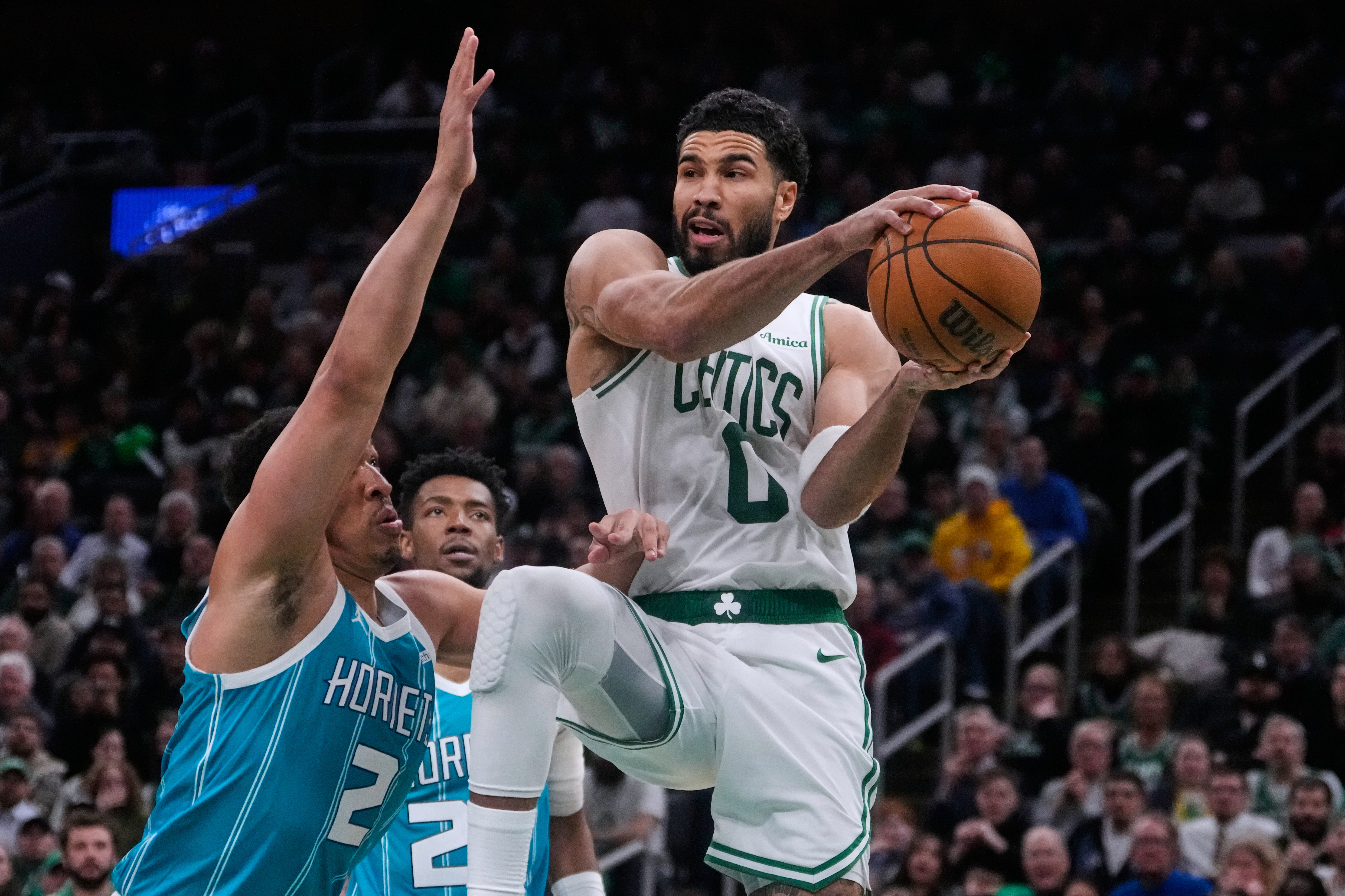 Boston Celtics forward Jayson Tatum (0) looks to pass while covered by Charlotte Hornets forward Grant Williams (2) during the second half of a NBA basketball game, Tuesday, April 7, 2026, in Boston. 