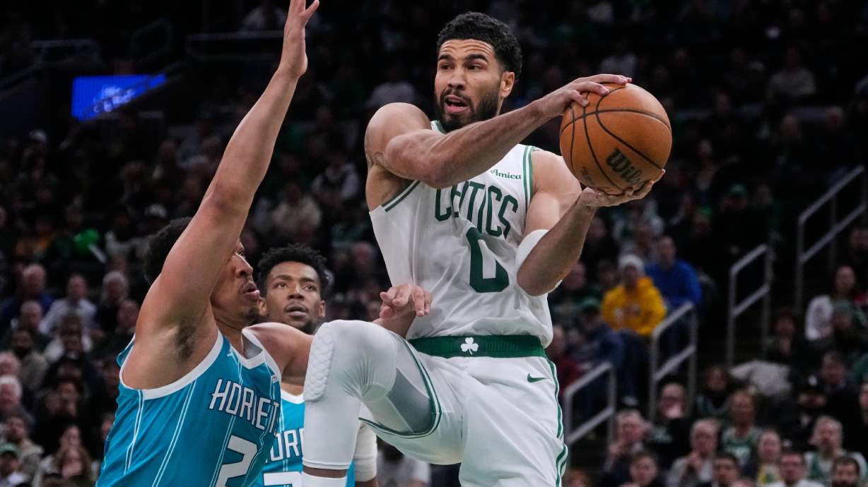 Boston Celtics forward Jayson Tatum (0) looks to pass while covered by Charlotte Hornets forward Grant Williams (2) during the second half of a NBA basketball game, Tuesday, April 7, 2026, in Boston.
