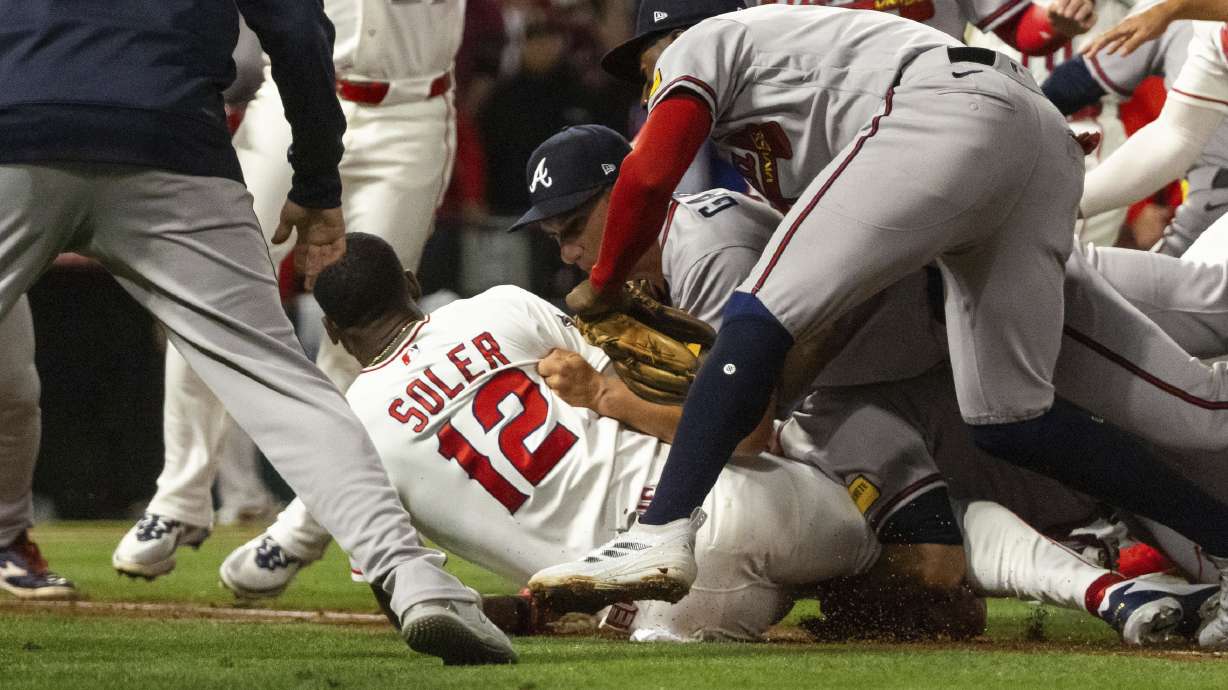 Los Angeles Angels' Jorge Soler (12) is tackled to the ground by Atlanta Braves players as a fight breaks out during the fifth inning of a baseball game, Tuesday, in Anaheim, Calif.