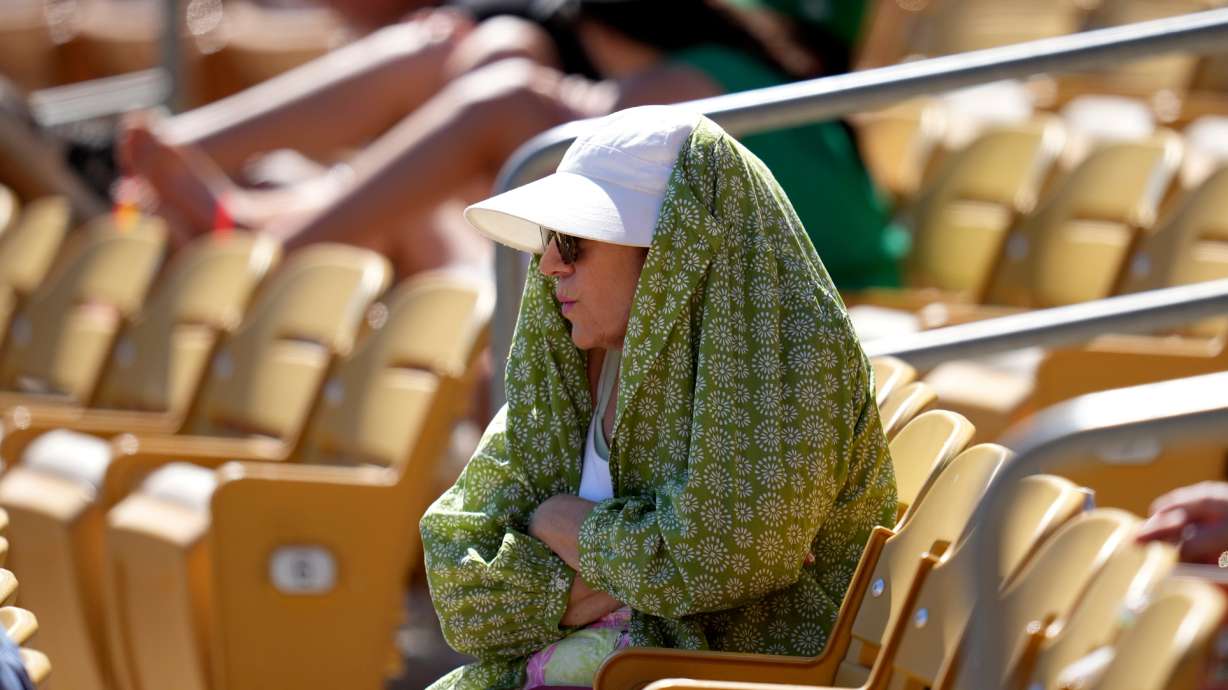 A baseball fan tries to shield from the sun during the fourth inning of a spring training baseball game between the Chicago White Sox and the Athletics, March 17, in Phoenix.