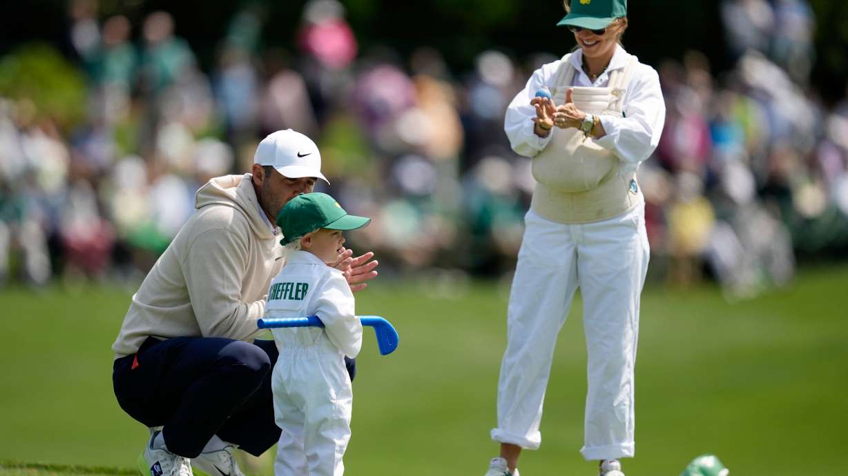 Scottie Scheffler, left, speaks with his son, Bennett, center, as his wife Meredith holds their son Remy, on the third hole during par-3 contest ahead of the Masters golf tournament at the Augusta National Golf Club, Wednesday, April 8, 2026, in Augusta, Ga.