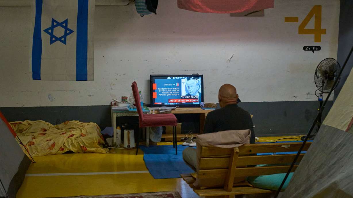 A man sits inside a shelter watching news after a two-week ceasefire with Iran was announced, in Tel Aviv, Israel, Wednesday. The ceasefire is now threatened after Israel hit Lebanon with more airstrikes, leading Iran to close the Strait of Hormuz again.