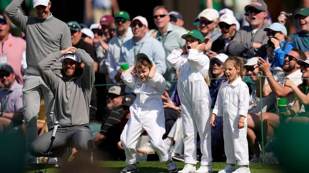 Rory McIlroy, from left, and Tommy Fleetwood react to a shot with his son, Franklin, Shane Lowry's daughter, Iris, and Rory McIlroy's daughter, Poppy, on the seventh hole during par-3 contest ahead of the Masters golf tournament at the Augusta National Golf Club, Wednesday, April 8, 2026, in Augusta, Ga.