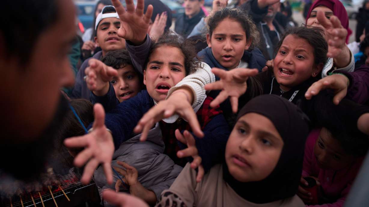 Displaced families extend their hands while waiting for donated food beside the tents they use as shelters after fleeing Israeli bombardment in southern Lebanon, in Beirut, Thursday.