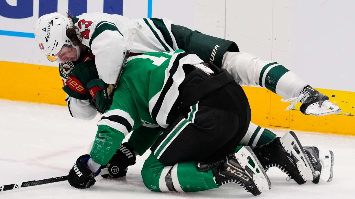 Minnesota Wild defenseman Quinn Hughes, top and Dallas Stars' Adam Erne (73) fight in the third period of an NHL hockey game Thursday, April 9, 2026, in Arlington, Texas.