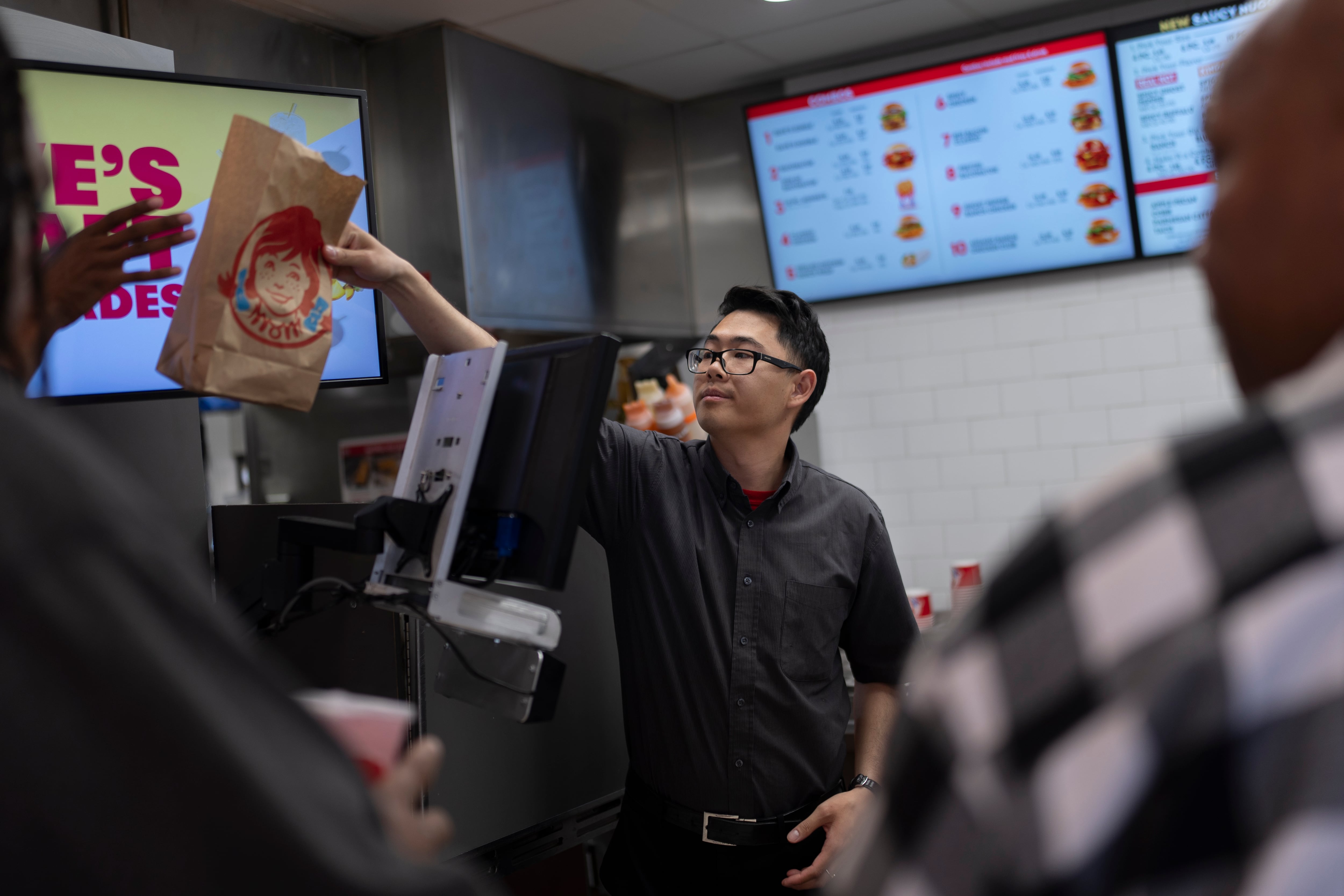 Lawrence Cheng, whose family owns seven Wendy's locations south of Los Angeles, hands an order to a customer at his Wendy's restaurant in Fountain Valley, Calif., June 20, 2024. Fast food jobs are popular for Utah teenagers in the summer.