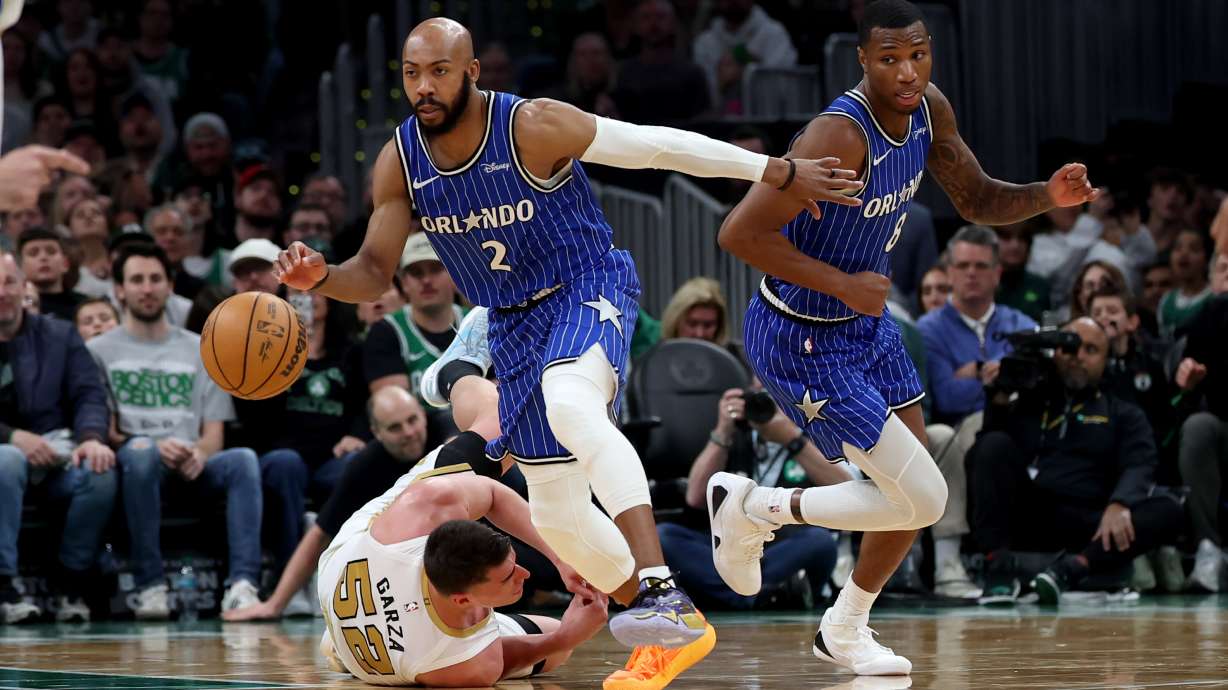 Boston Celtics forward Luka Garza (52) falls to the court as Orlando Magic guard Jevon Carter (2) and forward Jamal Cain (8) take control of the ball during the second half of an NBA basketball game, Sunday, April 12, 2026, in Boston.