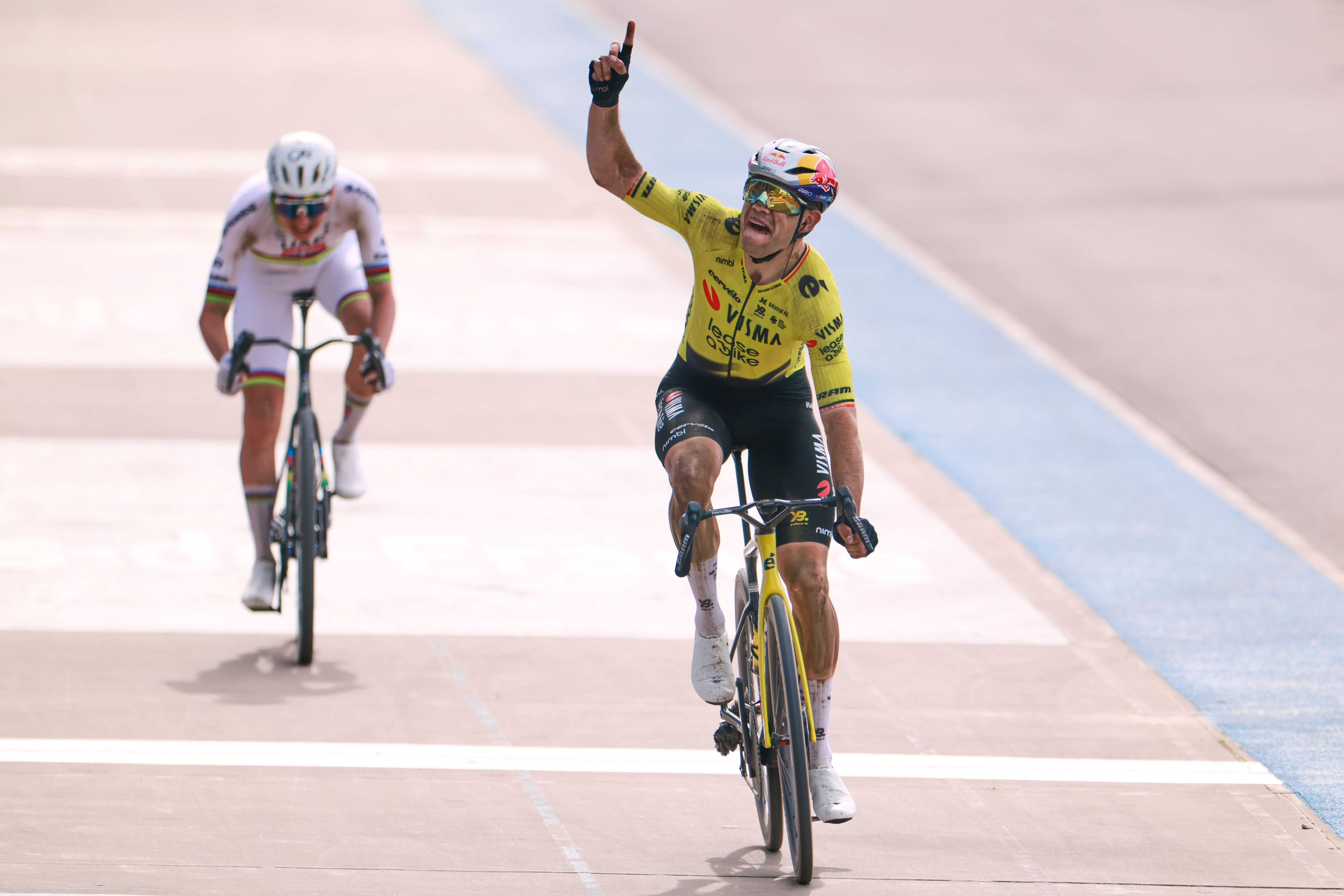 Belgium's Wout van Aert crosses the finish line ahead of Tadej Pogacar of Slovenia, left, to win the Paris-Roubaix cycling race in Roubaix, France, Sunday, April 12, 2026. Van Aert pointed his finger skywards to commemorate Belgian cyclist Michael Goolaerts who died after crashing in the race in 2018.